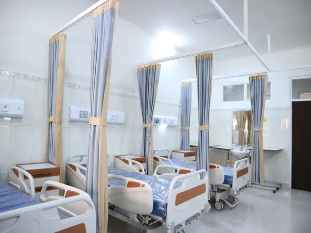 Modern kórházi kórterem ágyakkal, ahol a képzett segédápoló dolgozik